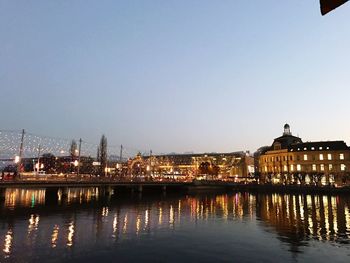 Illuminated bridge over river in city against sky