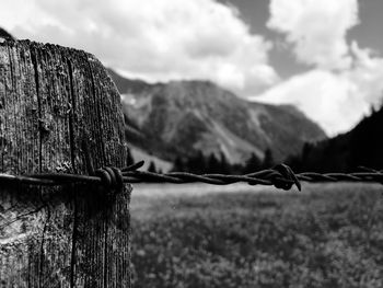 Close-up of barbed wire fence on land against sky