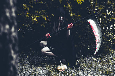 Woman in halloween costume holding while sitting on field