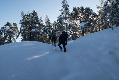 Rear view of people walking on snow covered landscape