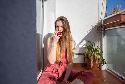 Portrait of young woman eating apple in balcony