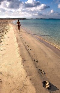 Woman walking on beach against sky