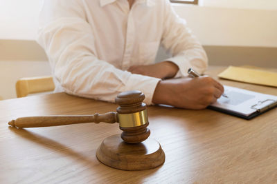 Midsection of man holding paper while sitting on table