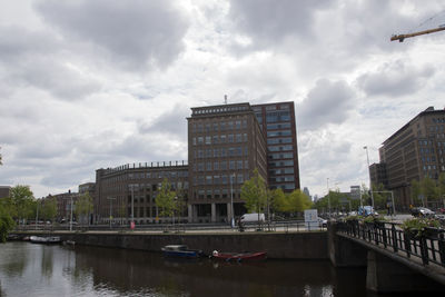 Bridge over river by buildings in city against sky