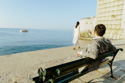 Man looking at woman walking on promenade against sky