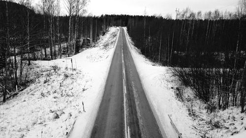 High angle view of road amidst snow covered field in forest
