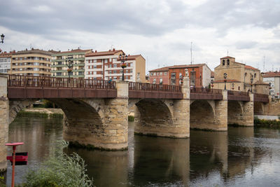 Bridge over river in city against sky