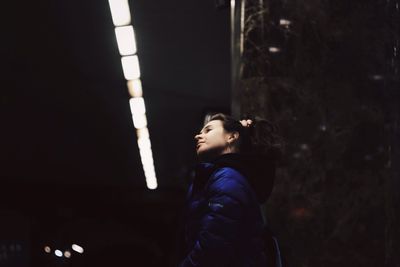 Side view of young woman standing at night