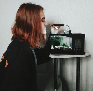 Side view of teenage girl standing by fish tank