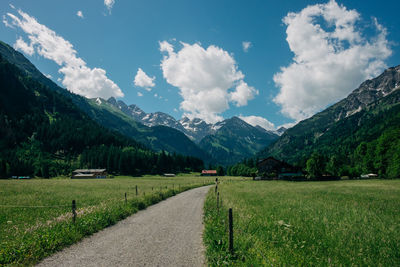 Road amidst green landscape and mountains against sky