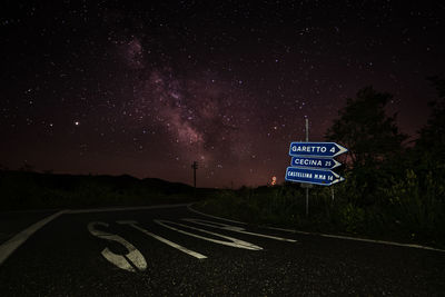 Road sign against sky at night