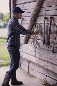 Full length of farmer arranging rope in barn