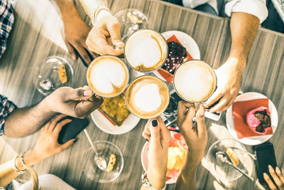 Cropped hands of friends toasting coffee cups at cafe