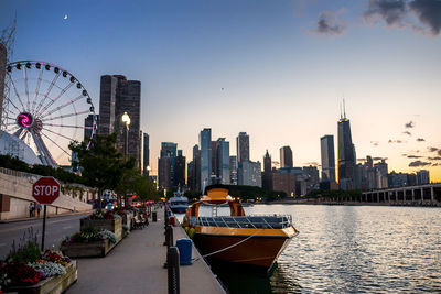 Boat moored on lake michigan against hancock building during sunset