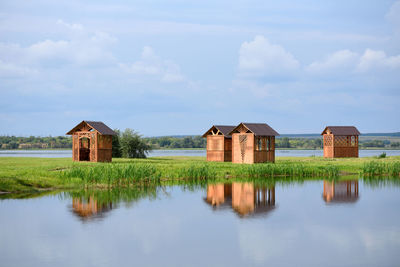 Houses by lake and buildings against sky