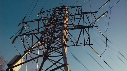 Low angle view of electricity pylon against clear blue sky