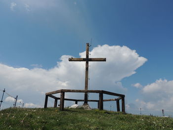 Low angle view of cross on land against sky