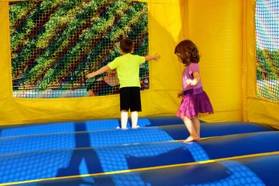 Siblings playing on bouncy castle