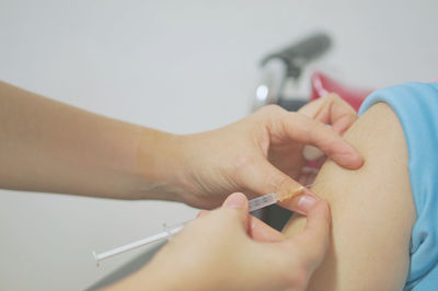 Cropped hands of doctor injecting on patient hand