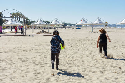 Rear view of kids running on beach