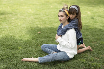 Full length of siblings sitting on field at park