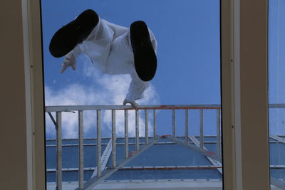 Directly below shot of man standing on glass against sky