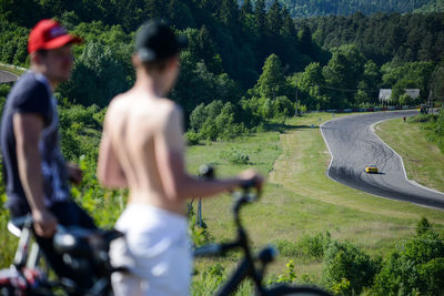 Rear view of people riding bicycle against trees