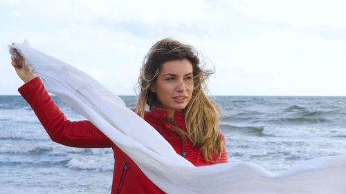 Portrait of smiling woman at beach against sky