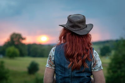 Woman wearing hat standing on field against sky