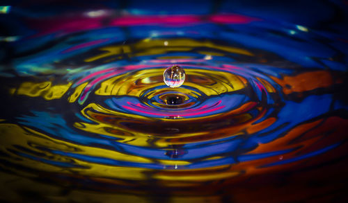 Close-up of drop falling in colorful water