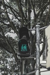 Low angle view of road sign against trees in city