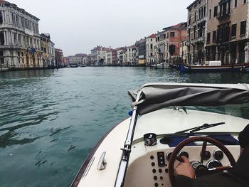 Boat in canal by buildings against sky