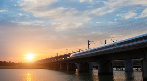 Bridge over river against sky during sunset