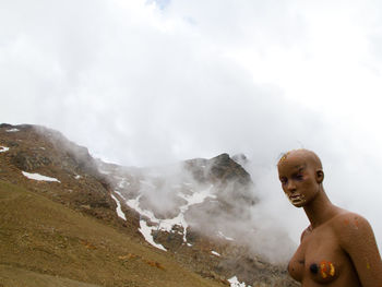 Full length of shirtless man in mountains against sky
