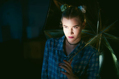 Beautiful young woman with umbrella looking away