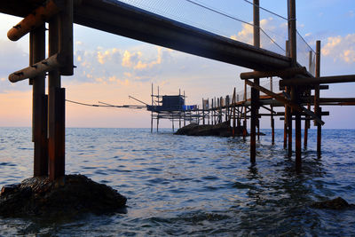 Pier over sea against sky during sunset