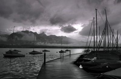 Boats in sea against cloudy sky