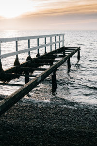 Pier on sea against sky during sunset