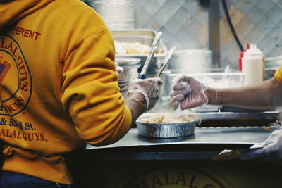 Midsection of people preparing food in commercial kitchen