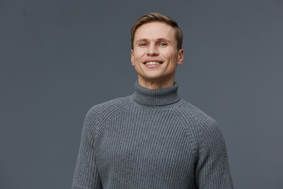 Portrait of young man standing against black background