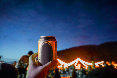 Close-up of man holding mobile phone against sky