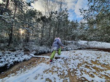 Woman standing on snow covered plants during winter