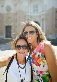 Portrait of friends in sunglasses standing against building