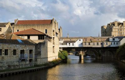 Arch bridge over river amidst buildings against sky