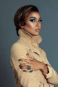 Portrait of young woman standing against blue background