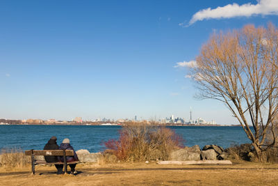 Man sitting by river against sky