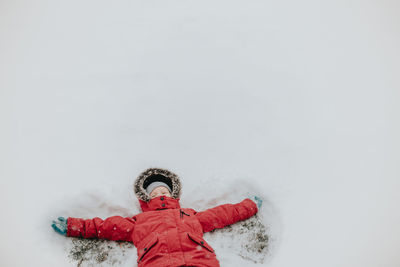 High angle view of girl making snow angel on land