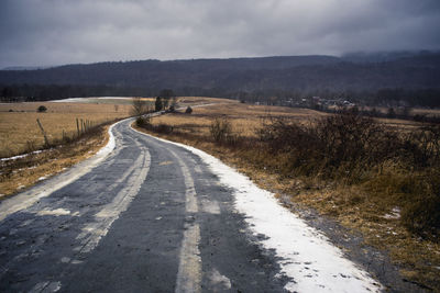 Road amidst field against sky