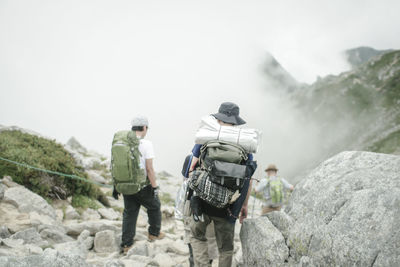 Rear view of people walking on rock against sky