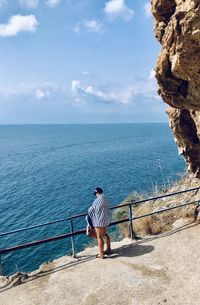 Rear view of man looking at sea against sky